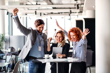 A group of business people standing in an office, expressing excitement.