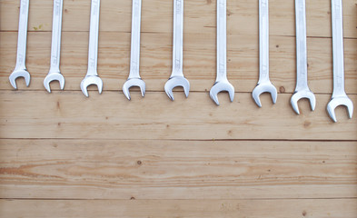 Set of wrenches lies on a wooden background in order