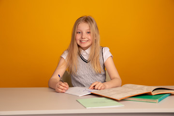 Happy child doing homework sitting isolated the bright yellow background