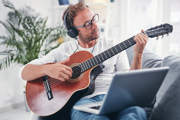 Obraz premium Man playing acoustic guitar in the living room.