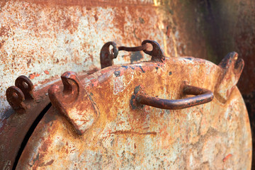 Old small rusty hatch oval door old boat weathered gray metal with lock rivets close-up background industrial
