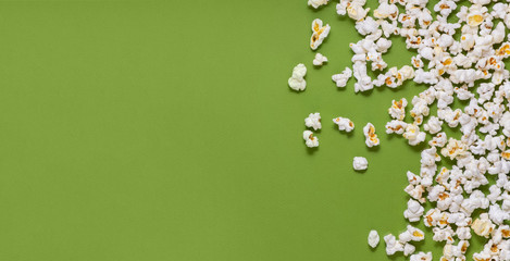 White tasty popcorn on a green background. Popcorn pattern on green background. Top view. Copyspace for your text.