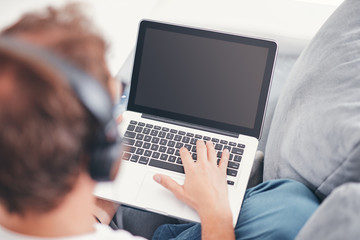 Man listening to music and using laptop in the living room.
