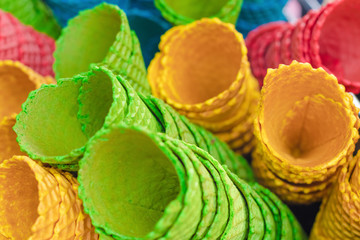 Piles of multi-colored tasty waffle cups in a cafe or shop, prepared for ice cream. Close-up, selective focus.