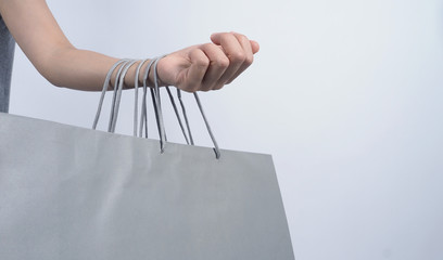 Fototapeta na wymiar Shopping bag grey color hold on by business asian woman arm and white background which represent shop sale season or online-shopping or e-commerce or clearence sales or shopaholic concept