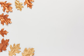 Autumn composition with a gold and copper spray painted natural leaves on white background. Flat lay, top view, copy space