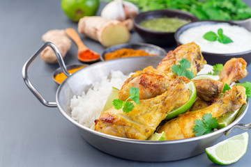 Indian chicken tandoori, marinated in greek yogurt  and spices, served with lime wedges, cilantro and basmati rice,  horizontal