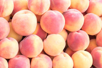 Peaches close-up. Organic peaches in pile  of farmers market. Peach harvest heap. Healthy vegan raw snack. Clean eating concept.