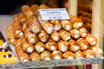 Closeup of cannoli stuffed with cream cheese whipped filling dessert on tray window display in gourmet bakery Italian cafe