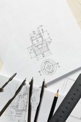 Compass legs on the background of the drawing. Nearby a ruler and a simple pencil. The drawing is...