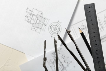 Compass legs on the background of the drawing. Nearby a ruler and a simple pencil. The drawing is...