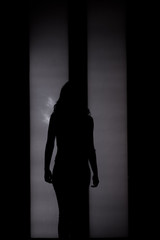 Woman silhouette in front of back-lighted door