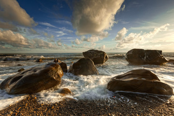 White waves crashing on the rocks at sunset