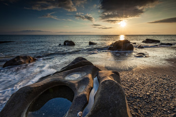 White waves crashing on the rocks at sunset