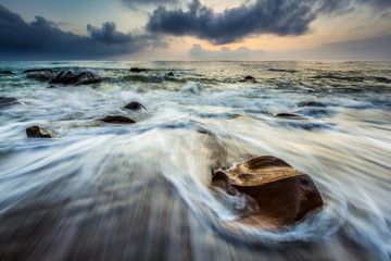 White waves crashing on the rocks at sunset