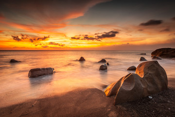 White waves crashing on the rocks at sunset