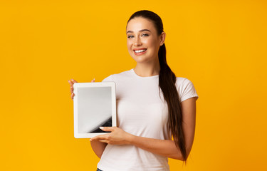 Cladful Lady Showing Digital Tablet Screen Over Yellow Background