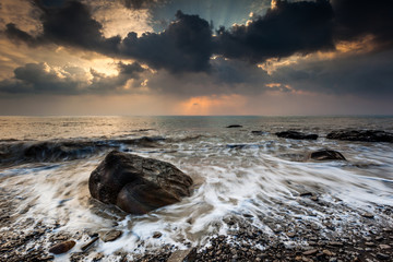 White waves crashing on the rocks at sunset
