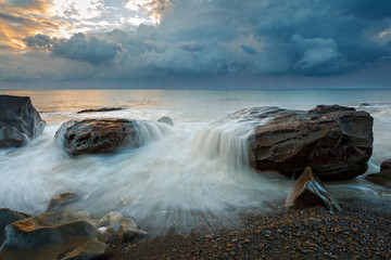 White waves crashing on the rocks at sunset