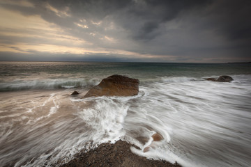 White waves crashing on the rocks at sunset