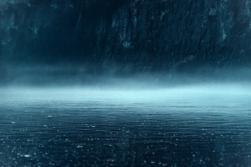 Thick night fog over the river with rocky shore