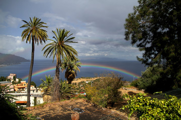 Fototapeta na wymiar amazing rainbow on the sky in taormina sicilt tourists taking photos