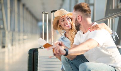 Loving couple in airport using travel app on smartphone