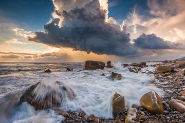 White waves crashing on the rocks at sunset