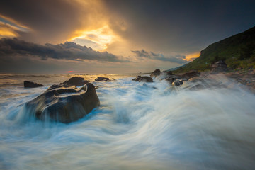 White waves crashing on the rocks at sunset