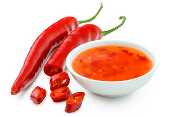 Sweet chilli sauce in a white ceramic bowl next to one whole and one cut red chilli isolated on...