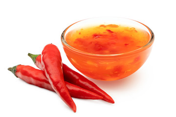 Sweet chilli sauce in a glass bowl next to three red chillies isolated on white.