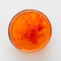 Sweet chilli sauce in a white ceramic bowl isolated on white from above.