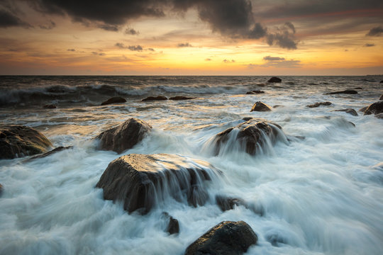 White waves crashing on the rocks at sunset