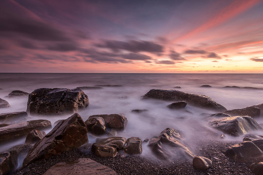 White waves crashing on the rocks at sunset