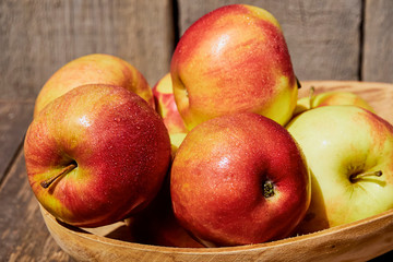 Fresh red apples with green leaves on a wooden old table. On a wooden background. Free space for text. soft focus