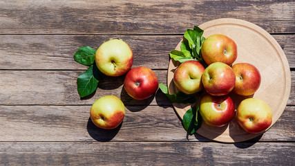 Fresh red apples with green leaves on a wooden old table. On a wooden background. Free space for text. view from above