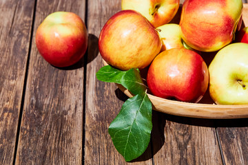 Fresh red apples with green leaves on a wooden old table. On a wooden background. Free space for text. soft focus