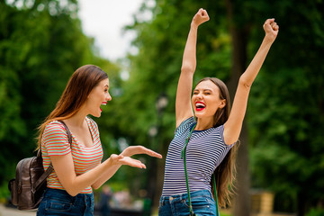 Portrait of delighted ladies with red lips stick screaming yeah raising fists closing eyes wearing...