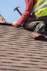 Workman install element of tile roof on new home under construction © brizmaker