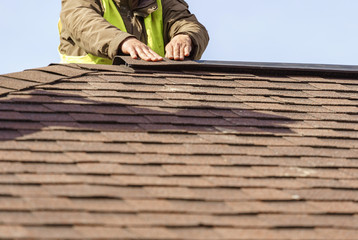 Workman install element of tile roof on new home under construction © brizmaker