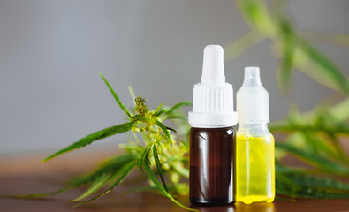 Cannabis plant herbal pharmaceutical CBD oil from jar. Wellness Hemp Cannabidiol. CBD oil bottles cannabis extract tincture liquid on wooden table. Medical marijuana concept. Place for copy space