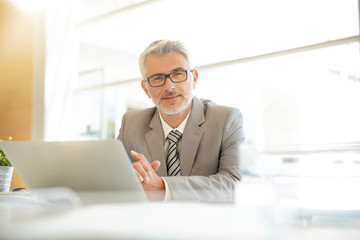 Mature businessman sitting at desk looking at camera