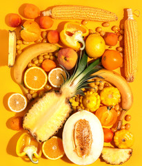 Assorted vegetables and fruits in yellow on a yellow background. Top view