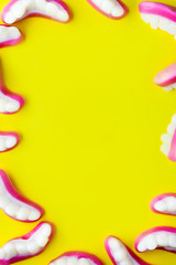 Halloween gummy milk teeth or sweet jelly candies frame template for text over bold yellow color background.Halloween candy for party,trick or treat concept.Flat lay,top view,copy space