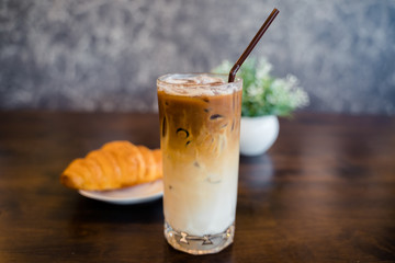 Closeup a glass of iced espresso machiano served with croissant