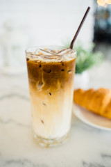 Closeup a glass of iced espresso machiano served with croissant