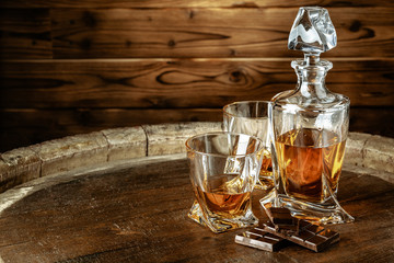 A bottle of cognac and glass on a brown wooden background. Brandy