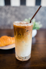 Closeup a glass of iced espresso machiano served with croissant