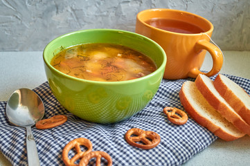 The usual home-made lunch. A Cup of soup with potatoes, carrots and beef. green tea and mini-brezel. Pieces of loaf.