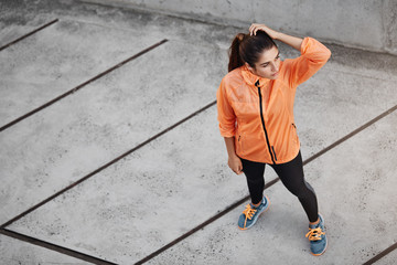 Sport, urban lifestyle and recreation concept. Upper view fit and appealing sportswoman in orange...